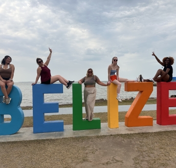 group of women on top of Belize letters